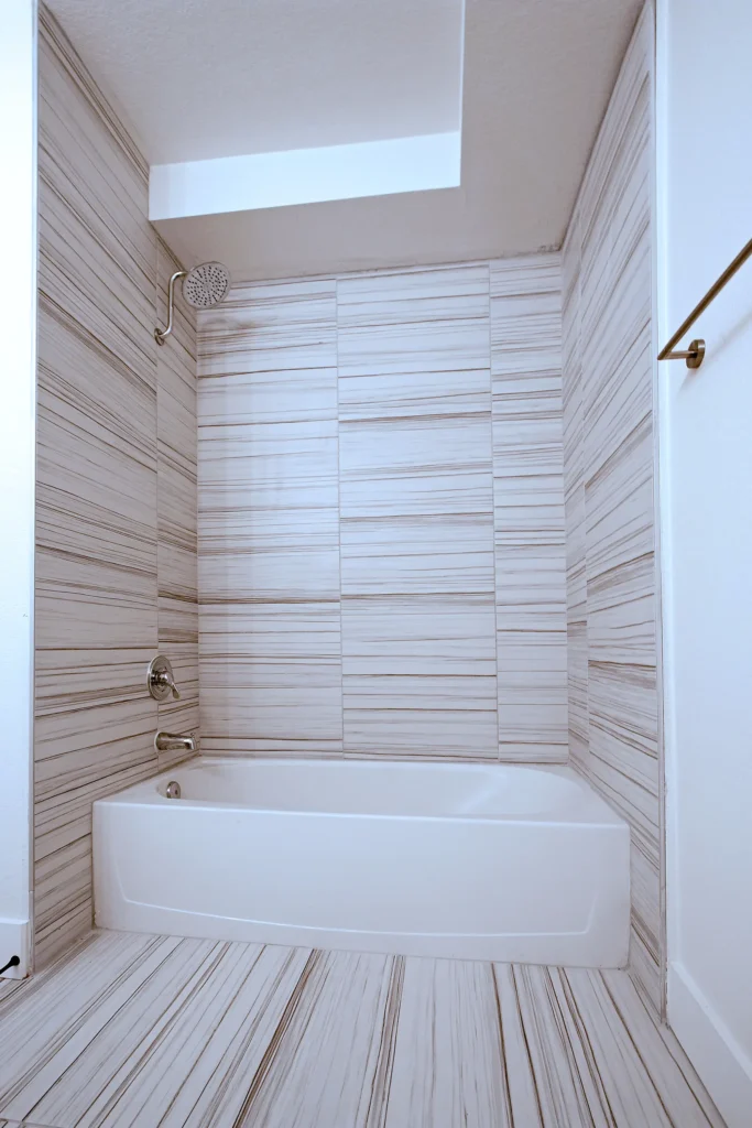 A clean bathroom featuring a bathtub and a shower, with neutral-colored tiles and modern fixtures.