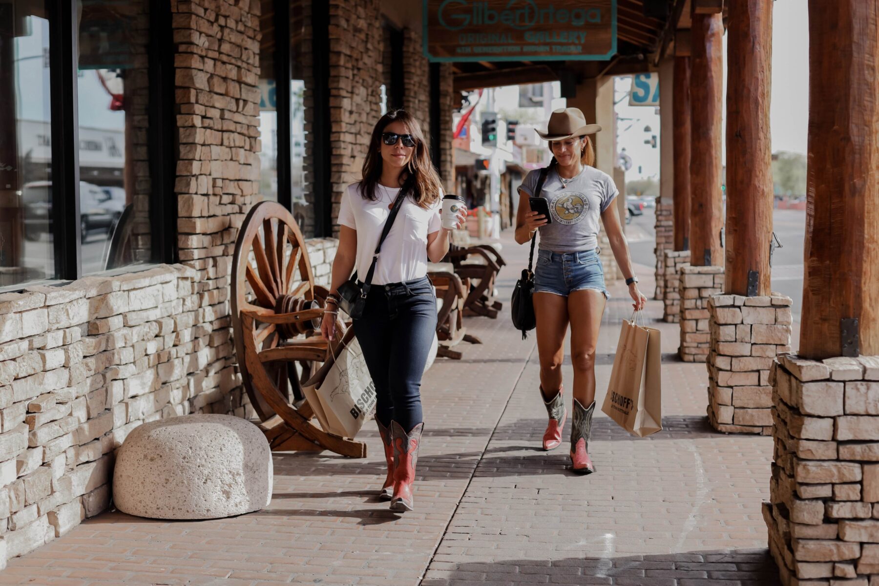 Two women shopping at outdoor mall wearing stylish cowboy boots.